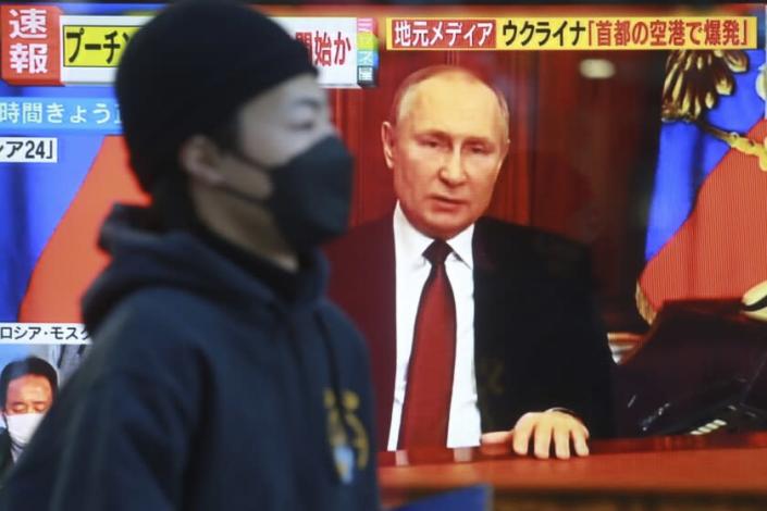 A man walks past a TV screen with image of Russia's President Vladimir Putin in Tokyo, Thursday, Feb. 24, 2022. As Russia intensifies its assault on Ukraine, it is getting a helping hand from China in spreading inflammatory and unsubstantiated claims that the U.S. is financing biological weapons labs in Ukraine. (AP Photo/Koji Sasahara, File)
