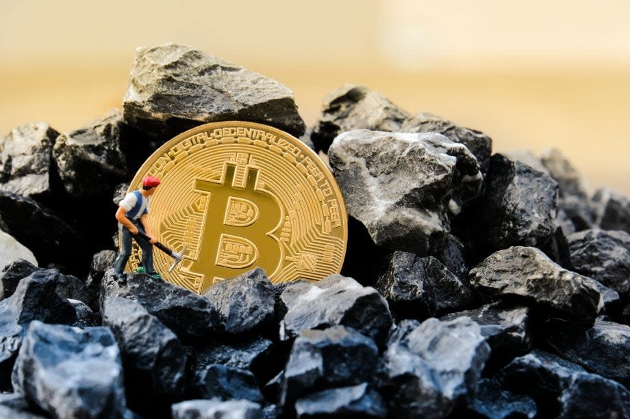 Bitcoin-Münuze auf einem Kohlehaufen, daneben die Modellfigur eines Minenarbeiters (Symbolbild Bitcoin Mining / Proof of Work)
