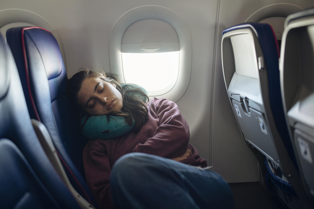 Young woman taking a nap in the airplane while traveling.