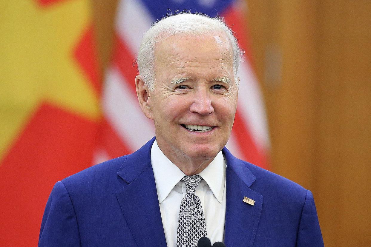 Joe Biden smiles for the camera, with the U.S. and Vietnamese flags in the background.