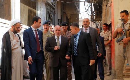 Iraqi Prime Minister Haider al-Abadi (C) walks after a meeting with the top Shiite cleric, Grand Ayatollah Ali al-Sistani, in the Shiite holy city of Najaf, south of Baghdad, October 20, 2014. REUTERS/Alaa Al-Marjani