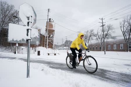 A bicyclist exits the Midtown Greenway bicycle and pedestrian trail during the spring snowstorm in Minneapolis, Minnesota, U.S., April 11, 2019. REUTERS/Annabelle Marcovici