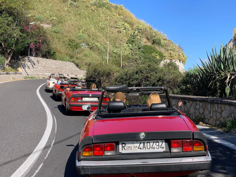 People driving vintage cars in Sicily, Italy.