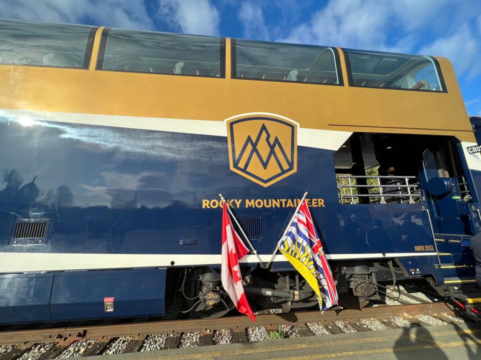 A large blue train with "Rocky Mountaineer" on side in gold letters