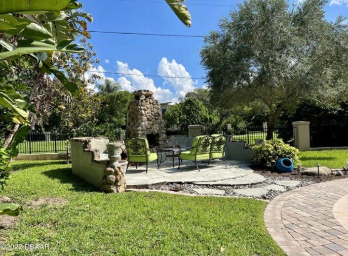 A covered patio, overlooking the “picture-postcard” backyard with this outdoor fireplace and seating area.