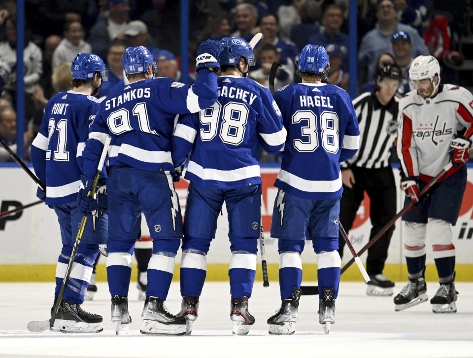 Tampa Bay Lightning center Brayden Point (21), center Steven Stamkos (91), defenseman Mikhail Sergachev (98) and left wing Brandon Hagel (38) celebrate after Sergachev's goal during the first period of an NHL hockey game against the Washington Capitals, Sunday, Nov. 13, 2022, in Tampa, Fla. (AP Photo/Jason Behnken)