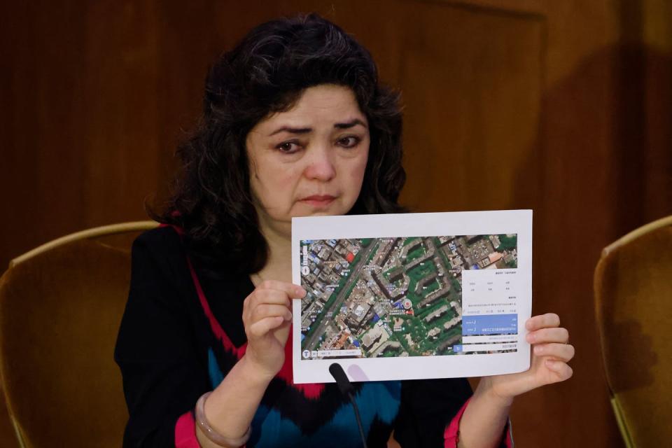 A woman has tears in her eyes as she holds up a satellite photograph