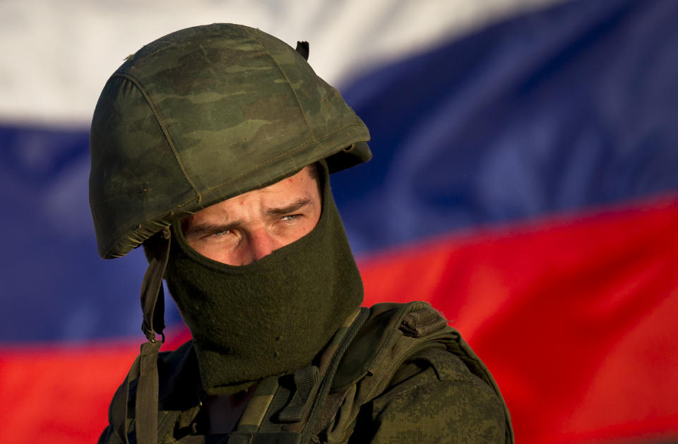 A pro-Russian soldier is back dropped by Russia's flag while manning a machine-gun outside an Ukrainian military base in Perevalne, Ukraine, Saturday, March 15, 2014. Tensions are high in the Black Sea peninsula of Crimea, where a referendum is to be held Sunday on whether to split off from Ukraine and seek annexation by Russia.(AP Photo/Vadim Ghirda)