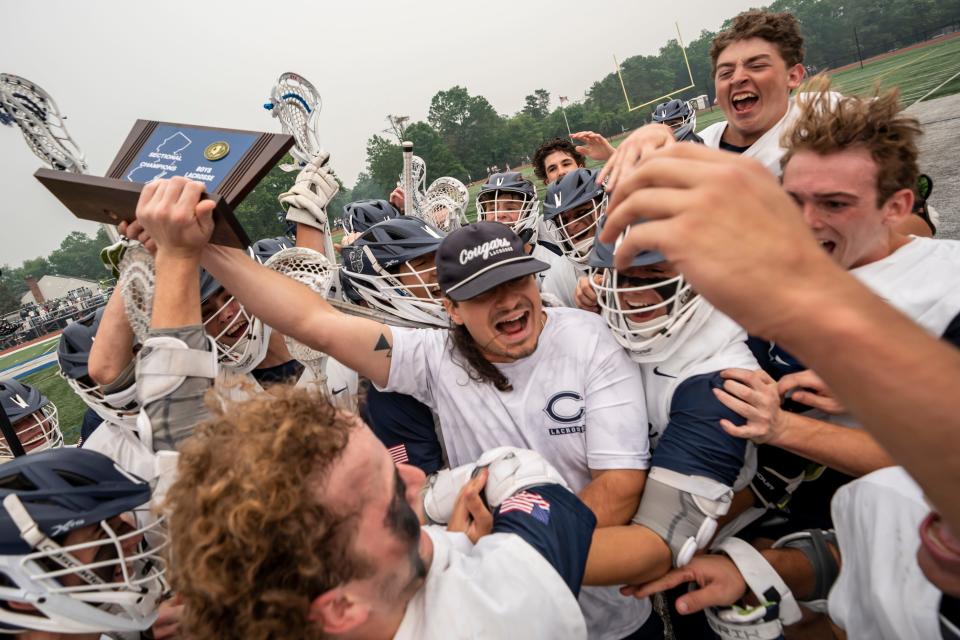 Chatham head coach Christian Scarpello holds the trophy as he and the team celebrate their 10-5 win. Chatham hosts Ridge in the NJSIAA Group 3 North boys lacrosse final on Tuesday, June 6, 2023. 