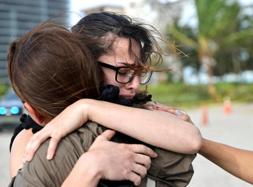 From left to right, Fayzah Bushnaq and Maria Fernanda Martinez comfort each other next to the Champlain Towers South Condo in Surfside, Florida, Friday, June 25, 2021. The apartment building partially collapsed on Thursday, June 24.