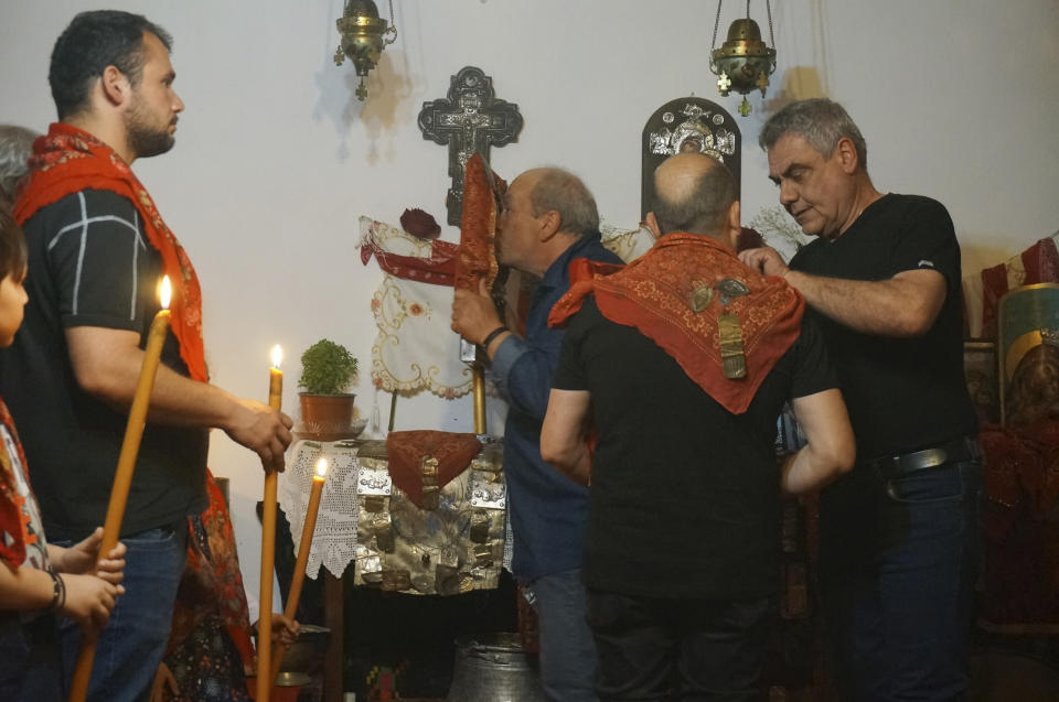 A group of "anastenaria" kiss icons and don red handkerchiefs before stepping out of a sacred space to walk on a bed of burning coals as part of centuries-old rituals kept alive in a smattering of villages like Lagkadas, Greece, on Monday, May 22, 2023. The associations of devotees of St. Constantine honor his feast day with dancing, prayer and firewalking. (AP Photo/Giovanna Dell'Orto)