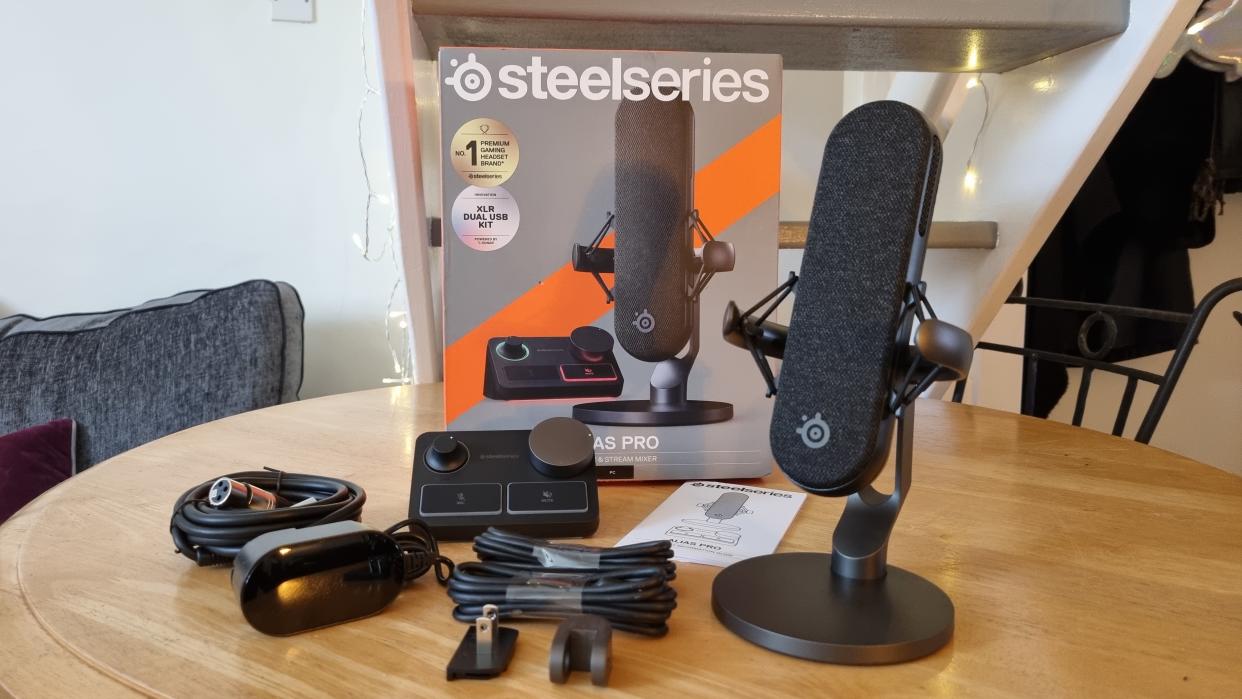  The SteelSeries Alias Pro with Stream Mixer and included cable, on a table with the packaging. 