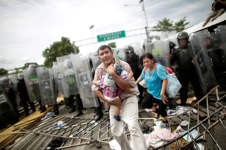 A Honduran migrant protects his child after fellow migrants, part of a caravan trying to reach the U.S., stormed a border checkpoint in Guatemala, in Ciudad Hidalgo, Mexico October 19, 2018. REUTERS/Ueslei Marcelino