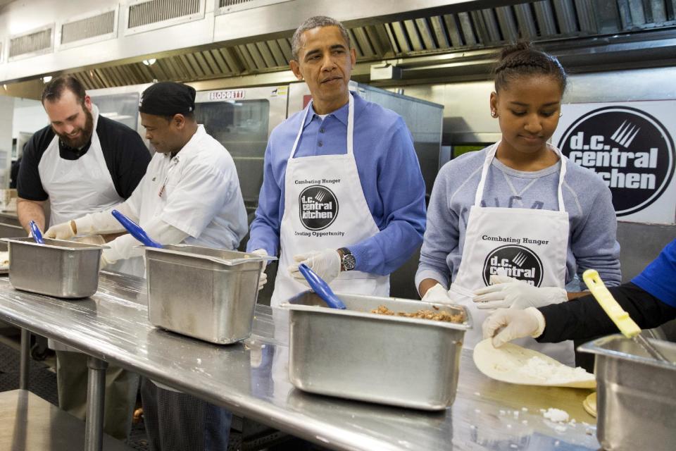 President Barack Obama and his daughter Sasha, right, make burritos at DC Central Kitchen as part of a service project in honor of Martin Luther King, Jr. Day, Monday, Jan. 20, 2014, in Washington. Also helping were first lady Michelle Obama and daughter Malia Obama. (AP Photo/Jacquelyn Martin)