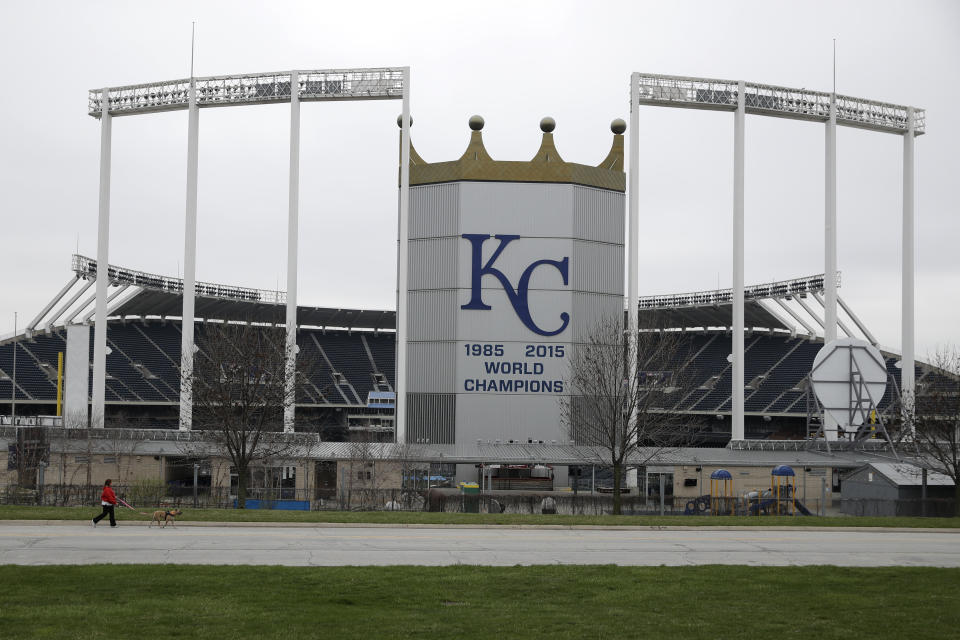 FILE - A woman and her dog walk past Kauffman Stadium, home of the Kansas City Royals baseball team, Wednesday, March 25, 2020, in Kansas City, Mo. Voter rejection of a stadium sales tax plan for the Kansas City Royals and Chiefs has raised questions about what happens next. (AP Photo/Charlie Riedel, File)