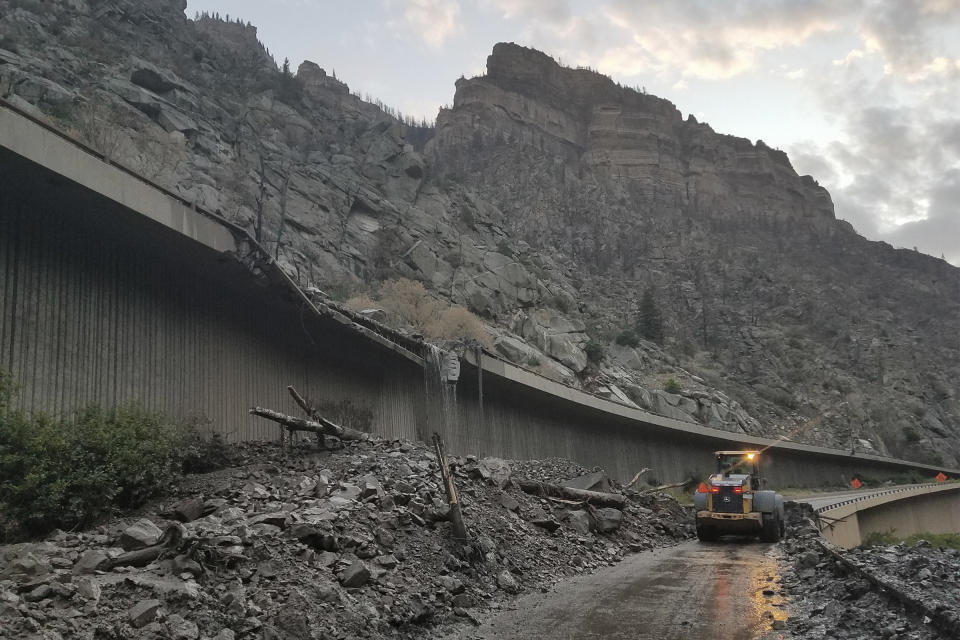 In this photo provided by the Colorado Department of Transportation, equipment works to clear mud and debris from a mudslide on Interstate-70 through Glenwood Canyon, Colo., on Friday, July 30, 2021. Authorities say more than 100 people had to spend the night on the highway, including nearly 30 who took refuge inside a highway tunnel along I-70 in Glenwood Canyon after rain over an area burned by a wildfire triggered the mudslides in Western Colorado. The people were caught with their vehicles Thursday night, July 29, 2021 and it took crews nine hours to carve out a path through the mud to reach them about 6:30 a.m. Friday, Garfield County Sheriff's Office spokesman Walt Stowe said. (Colorado Department of Transportation via AP)