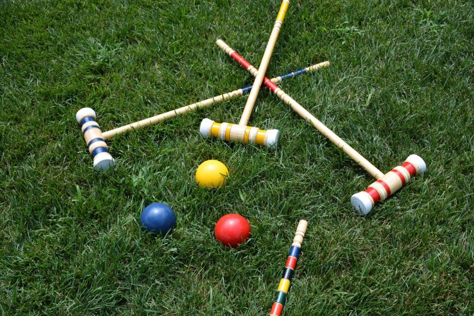 high angle view of multi colored croquet balls and mallets on grass lawn