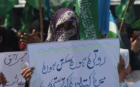 A woman holds up a placard in Lahore, Pakistan - Credit: AFP/Getty Images