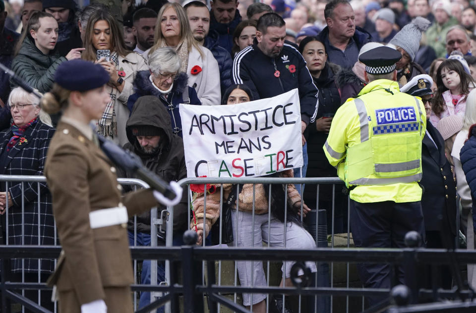 A woman holds a banner reading "Armistice means ceasefire" during a Remembrance Sunday service at Leeds War Memorial in Leeds, England, Sunday, Nov. 12, 2023. Every year, members of the British Royal family join politicians, veterans and members of the public to remember those who have died in combat. (Danny Lawson/PA via AP)