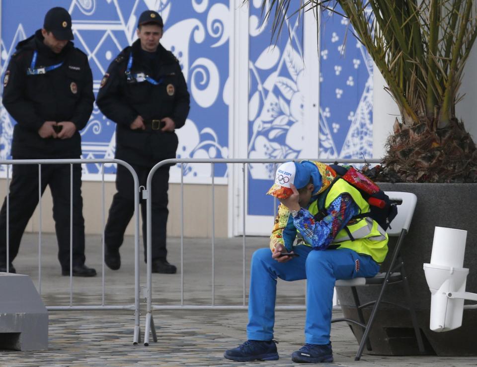 A volunteer sits down as security guards patrol at the Olympic Park in Adler near Sochi January 16, 2014. President Vladimir Putin said on Thursday no athlete would face discrimination at next month's Winter Olympics, hoping to ease international concern over a Russian law banning gay "propaganda". REUTERS/Alexander Demianchuk (RUSSIA - Tags: SPORT OLYMPICS POLITICS CRIME LAW)