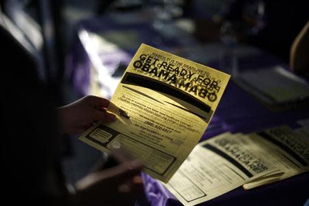 A woman picks up a leaflet at a health insurance enrollment event in Cudahy, California March 27, 2014. REUTERS/Lucy Nicholson