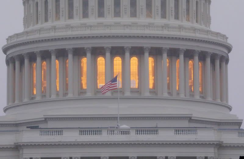 FILE PHOTO: A United States flag flies in front of the U.S. Capitol dome at sunrise in Washington