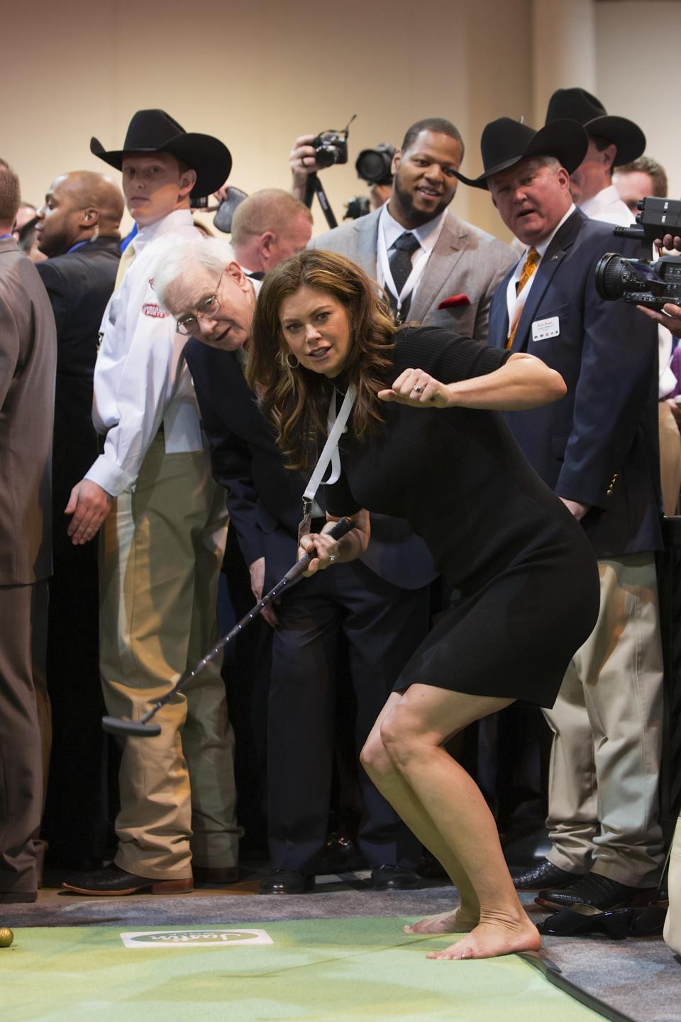 Former model and current businesswoman Kathy Ireland follows the path of her putt with Warren Buffett behind her, at the Justin Boots indoor mini golf lane in Omaha, Neb., Saturday, May 4, 2013, at the annual Berkshire Hathaway shareholder meeting. (AP Photo/Nati Harnik)