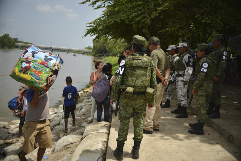 Mexican migration officials check the identification cards of people crossing the Suchiate River where Mexican National Guards (GN) stand guard, during a press tour of their work organized by the GN near Ciudad Hidalgo, Mexico, Wednesday, July 3, 2019. A National Guard commander explained to the agents that they were there to support immigration enforcement, but not to interfere in the brisk and vital commerce carried out on rafts that shuttle all manner of goods between the two countries. (AP Photo/Idalia Rie)