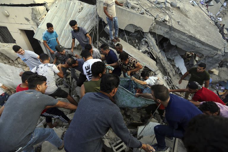 Los palestinos llevan el cuerpo de una persona fallecida que fue encontrado bajo los escombros de una iglesia ortodoxa griega, después de los ataques aéreos israelíes en la ciudad de Gaza, el viernes 20 de octubre de 2023. 