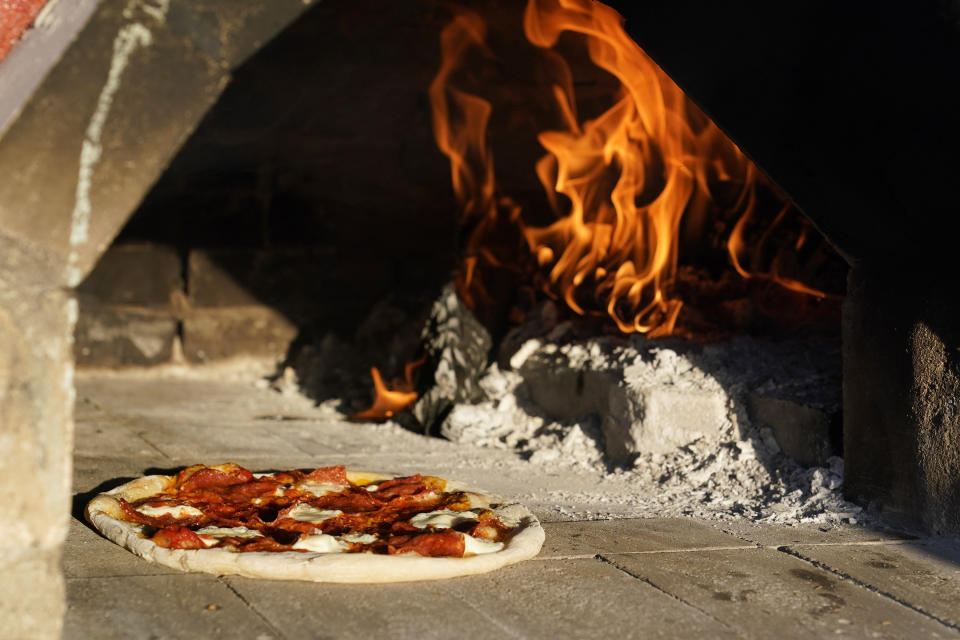 A pizza cooks in an outdoor pizza oven on April 3, 2021, in Scottsdale, Ariz. Beaten down by the pandemic, some laid-off or idle restaurant workers have pivoted to dishing out food from home. (AP Photo/Ross D. Franklin)