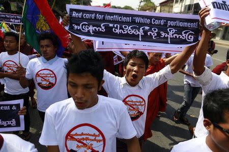 A man holds up a banner during a protest to demand the revocation of the right of holders of temporary identification cards, known as white cards, to vote, in Yangon February 11, 2015. REUTERS/Soe Zeya Tun