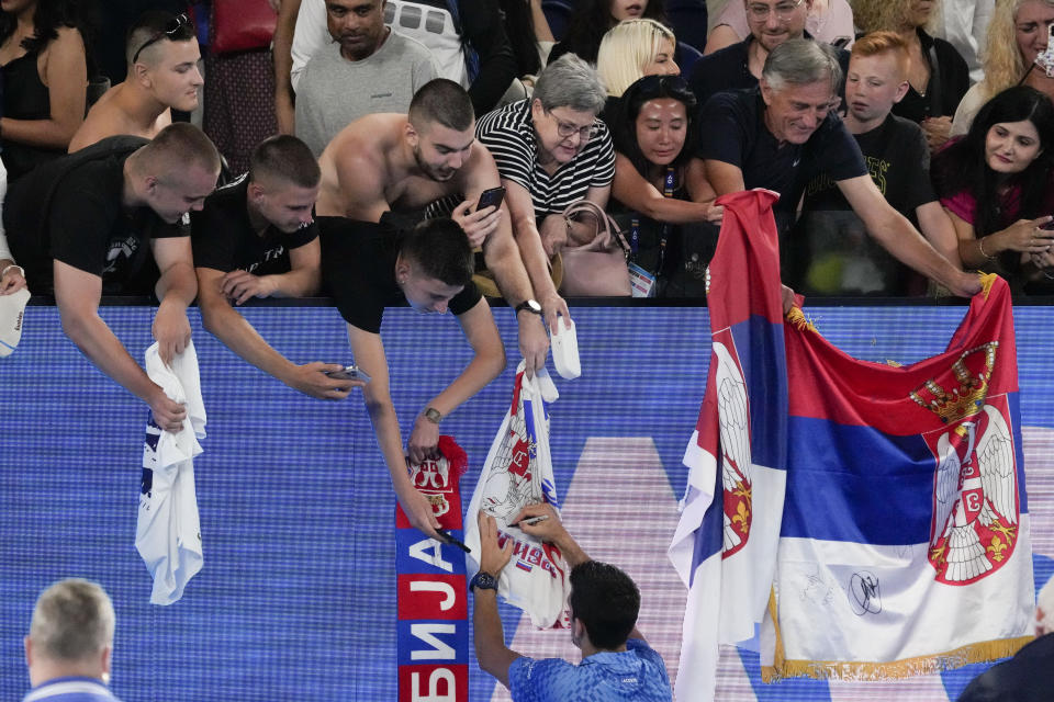 Novak Djokovic of Serbia signs autographs after defeating Roberto Carballes Baena of Spain in their first round match at the Australian Open tennis championship in Melbourne, Australia, Wednesday, Jan. 18, 2023. (AP Photo/Aaron Favila)