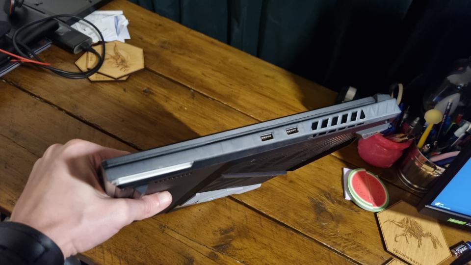 A reviewers fair hand holding the Asus ROG Strix Scar 18 on it's size for a look at its massive dimensions