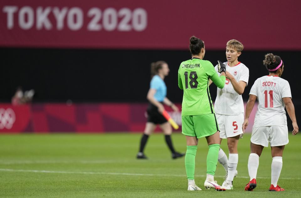 Canada's goalkeeper Kailen Sheridan, left, and Canada's Quinn, center, celebrate at the end of women's soccer match against Chile at the 2020 Summer Olympics, Saturday, July 24, 2021, in Sapporo, Japan. (AP Photo/Silvia Izquierdo)