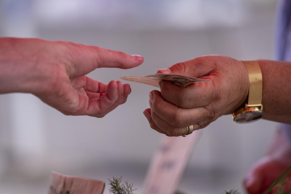 A customer pays using Croatian Kuna note at the vegetable market in downtown Zagreb, Croatia, Tuesday, July 12, 2022. The European Union is set to remove the final obstacles for Croatia to adopt the euro, ensuring the first expansion of the currency bloc in almost a decade. (AP Photo/Darko Bandic)