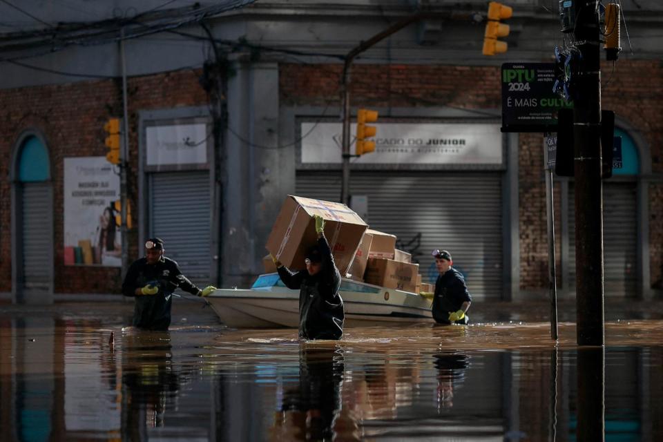 PHOTO: Men carry and move packages along a flooded street in the historical city center of Porto Alegre, Rio Grande do Sul state, Brazil, May 14, 2024.  (Anselmo Cunha/AFP via Getty Images)