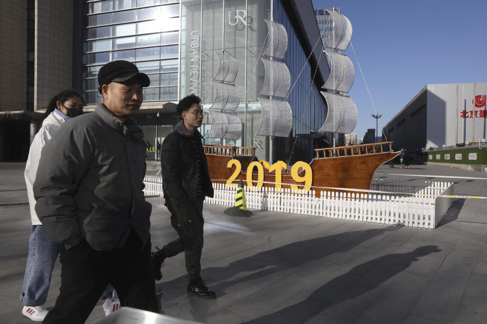 In this Friday, Jan. 4, 2019, photo, Chinese residents pass by a decor marking the new year outside a shopping mall in Beijing. A U.S. delegation led by deputy U.S. trade representative, Jeffrey D. Gerrish arrived in the Chinese capital ahead of trade talks with China. China sounded a positive note ahead of trade talks this week with Washington, but the two sides face potentially lengthy wrangling over technology and the future of their economic relationship. (AP Photo/Ng Han Guan)