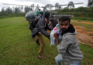 <p>Flood victims unload food and relief material from an Indian Air force helicopter at Nelliyampathy Village, in the southern state of Kerala, India. (Reuters) </p>