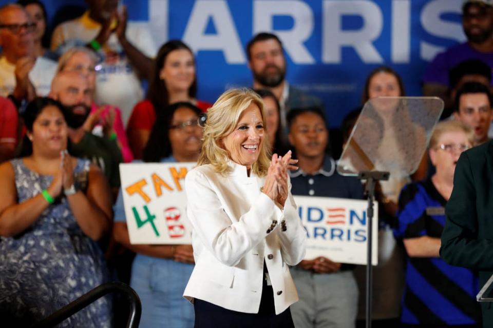 Jill Biden smiles on stage in front of a cheering crowd.