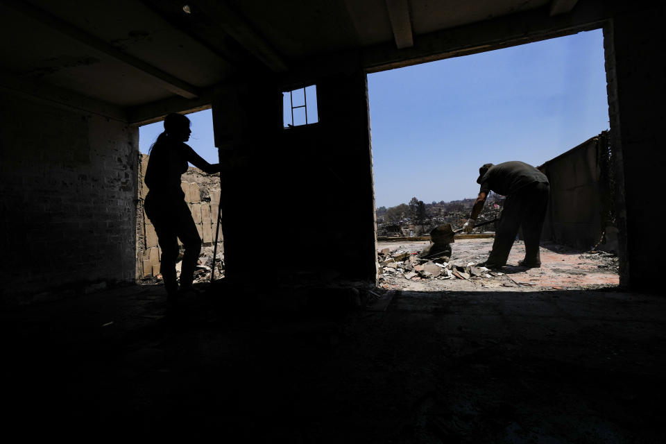 Residents clean up amid the rubble of homes burned by deadly forest fires in Vina del Mar, Chile, Monday, Feb. 5, 2024. (AP Photo/Esteban Felix)