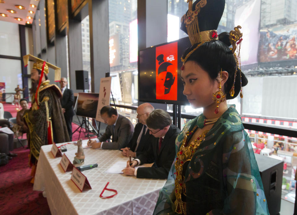 Two costumed members of "The Legend of Emperor Qin" show flank President Wang Yong, seated left, of Shaanxi Miracle Achievements Development Co., Chairman Robert Nederlander Sr., seated center, and President and CEO Robert Nederlander Jr., of Nederlander Worldwide Entertainment, as they sign an agreement to manage and produce a live show in a planned specially built $65 million theater in central China, in New York, Wednesday, Aug. 28, 2013. The show will feature music and dance in a high-tech 2,000 seat theater adjacent to the Terra Cotta Warriors and Horses exhibition, in Xian, China. (AP Photo/Richard Drew)