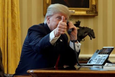 U.S. President Donald Trump gives a thumbs-up to reporters as he waits to speak by phone with Saudi Arabia's King Salman in the Oval Office at the White House in Washington, U.S. January 29, 2017. REUTERS/Jonathan Ernst