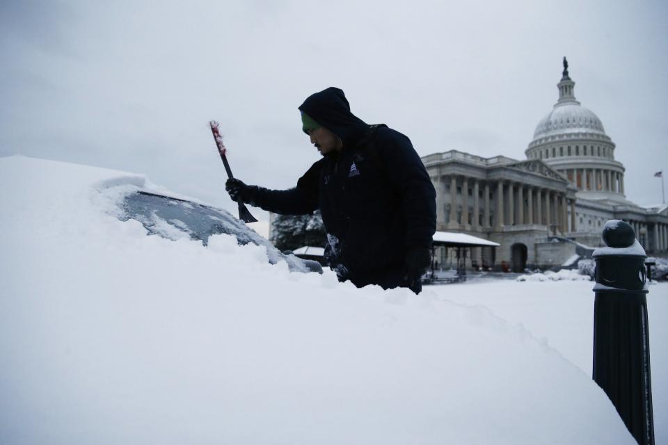 After finishing an overnight shift, a worker clears the snow from his car at the U.S. Capitol in Washington March 17, 2014. A winter storm landed a final punch on the U.S. mid-Atlantic states on Monday just days before spring begins, dumping more than a foot (30 cm) of snow in some places, shutting schools and federal offices and cancelling flights. The winter storm shut down federal offices in the nation's capital, and dozens of schools in the area also remained closed. (REUTERS/Jonathan Ernst)