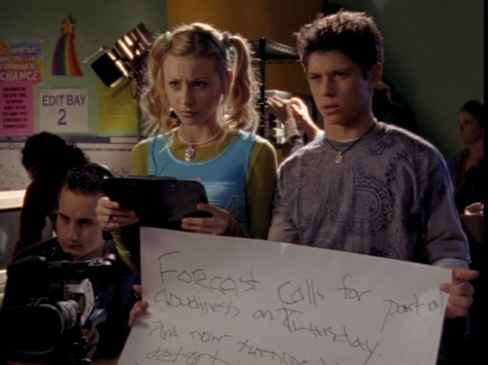 Aly Michalka stands beside Ricky Ullman, who is holding a poorly written cue card