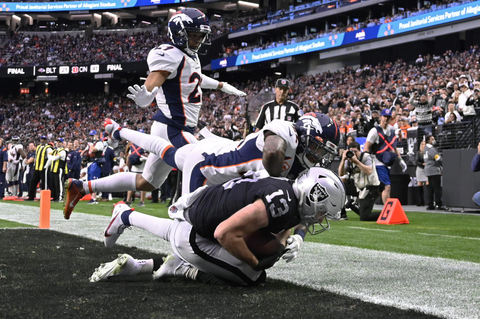 Las Vegas Raiders wide receiver Hunter Renfrow (13) catches a pass for a touchdown against Denver Broncos safety Kareem Jackson (22) during the first half of an NFL football game, Sunday, Dec. 26, 2021, in Las Vegas. (AP Photo/David Becker)