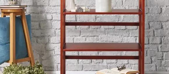 A bookcase in front of a white brick wall