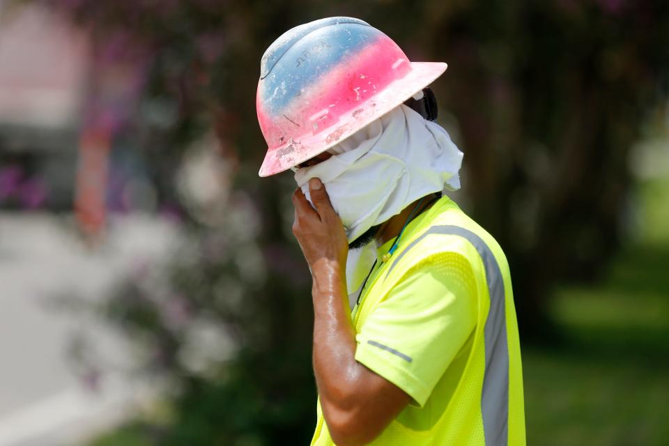 Construction worker Dineose Vargas wipes his face at a construction site on the Duncan Canal in Kenner, Louisiana, Tuesday, Aug. 13, 2019.