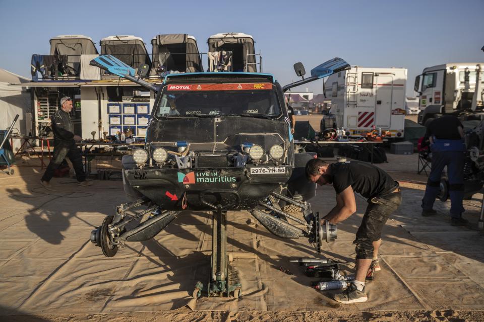 In this Monday, Jan. 13, 2020 photo, a mechanic works on a car after stage eight of the Dakar Rally in Wadi Al Dawasir, Saudi Arabia. Formerly known as the Paris-Dakar Rally, the race was created by Thierry Sabine after he got lost in the Libyan desert in 1977. Until 2008, the rallies raced across Africa, but threats in Mauritania led organizers to cancel that year's event and move it to South America. It has now shifted to Saudi Arabia. The race started on Jan. 5 with 560 drivers and co-drivers, some on motorbikes, others in cars or in trucks. Only 41 are taking part in the Original category. (AP Photo/Bernat Armangue)