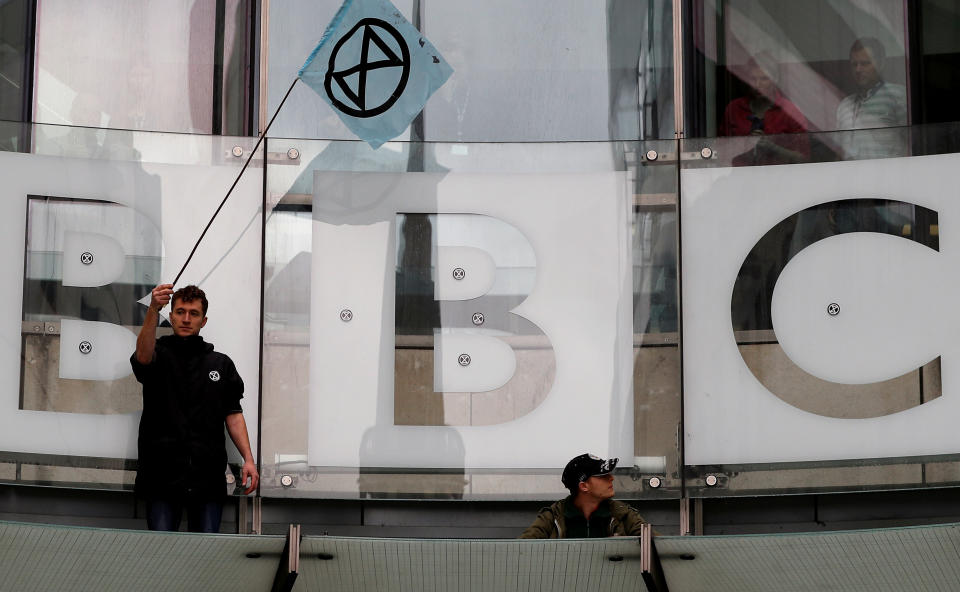 A protester waves a flag next to the BBC logo at the company's headquarters during an Extinction Rebellion demonstration in London, Britain October 11, 2019. REUTERS/Peter Nicholls