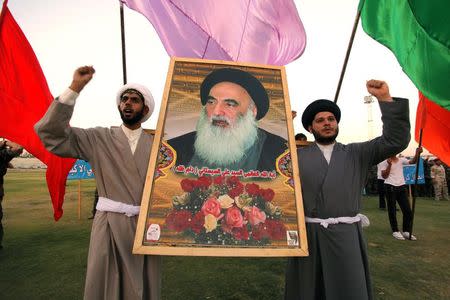 Shi'ite volunteers, who have joined the Iraqi army to fight against militants of the Islamic State, formerly known as the Islamic State in Iraq and the Levant (ISIL), carry a picture of Grand Ayatollah Ali Sistani during a graduation ceremony after completing their field training in Najaf, in this August 16, 2014 file photo. REUTERS/Alaa Al-Marjani/Files